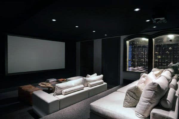 Home theater featuring white couches, a large screen, and wine storage on the side wall