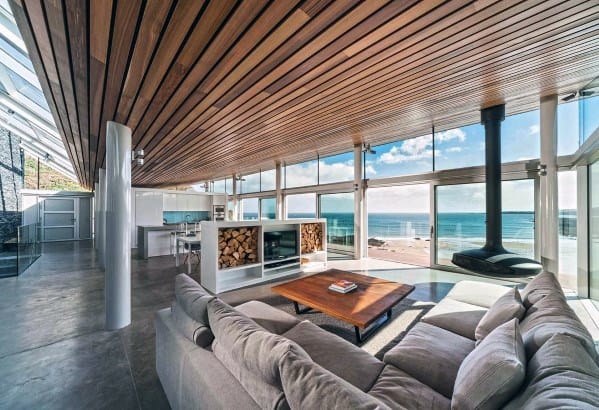 Modern open-concept living room with slatted wood ceiling, large sectional sofa, and fireplace.