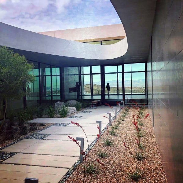 stone path surrounded by gravel garden with red plants 