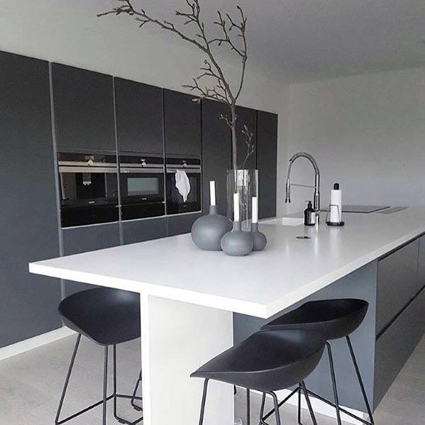 Minimalist grey kitchen with white countertops, built-in appliances, and black bar stools.