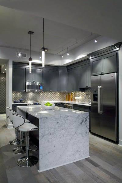 Modern kitchen with dark cabinets, marble island, stainless steel appliances, and mosaic backsplash.