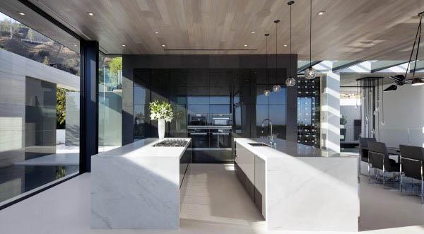 Modern kitchen with marble counters, sleek black cabinets, and floor-to-ceiling glass walls.