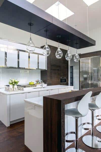 Contemporary kitchen with white cabinets, wood accents, glass pendant lights, and bar seating.