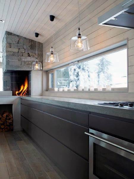 Modern kitchen with sleek dark cabinetry, wood ceiling accents, and a cozy stone fireplace.