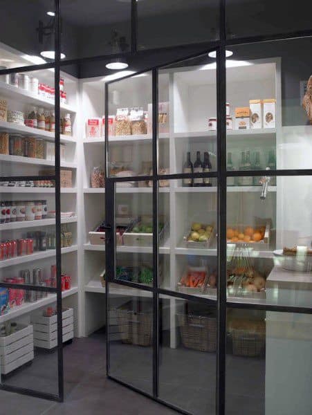 Modern pantry with glass doors, white shelves, and neatly organized food items.