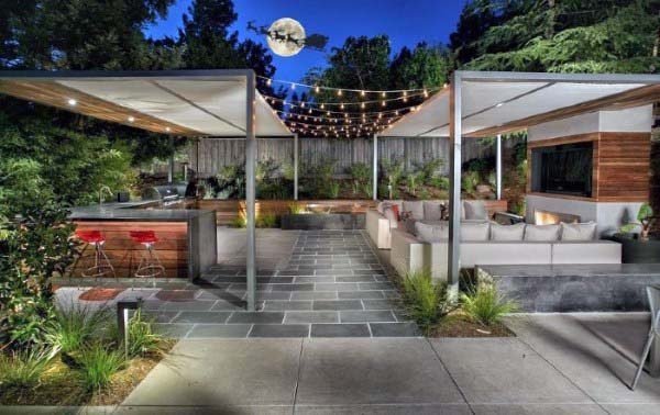 Modern outdoor lounge with string lights, sleek pergolas, stone flooring, and bar seating.