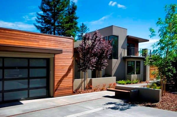 Contemporary home with wooden accents, minimalist landscaping, and a concrete driveway.
