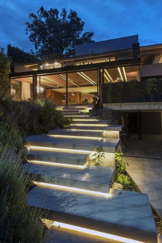 Contemporary house with illuminated floating steps leading to a glass-walled living space.