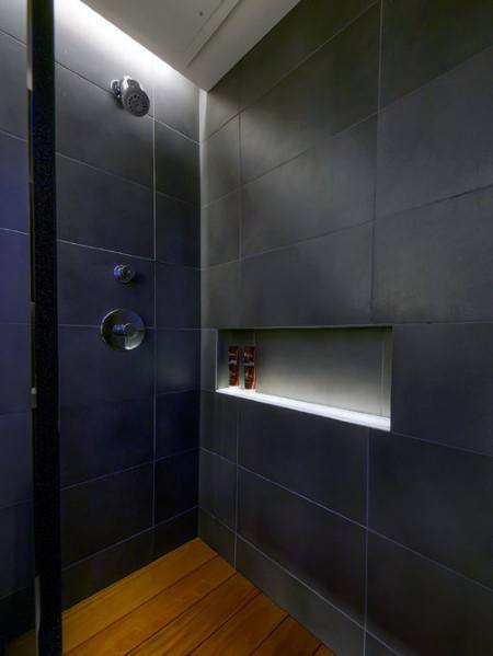 Modern shower with sleek black tiles and subtle LED lighting highlighting the storage niche for a clean, contemporary look