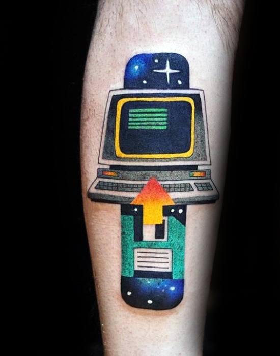 Colorful tattoo of a retro computer with a floppy disk and upload arrow, set against a galaxy background with stars and deep space tones.
