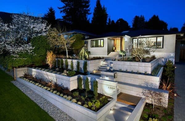 Terraced modern front yard with minimalist landscaping and outdoor lighting at dusk.