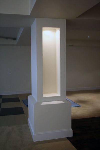 Modern basement pole cover with built-in recessed lighting and neutral decor.