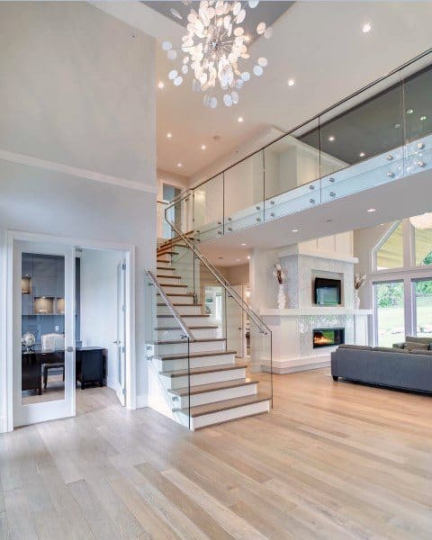 Spacious modern living room featuring a sleek staircase, fireplace, and elegant chandelier