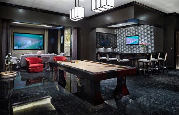 Luxurious man cave with a pool table, bar area, and large TV screens featuring black and red decor with modern lighting