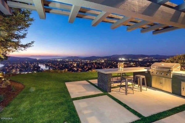 Modern outdoor BBQ grill bar with stunning panoramic views, sleek countertops, and a pergola-covered patio.