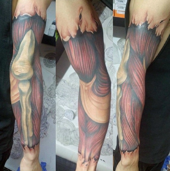 Full-sleeve anatomical tattoo revealing detailed muscle fibers and bones beneath torn skin, creating a hyper-realistic 3D effect.
