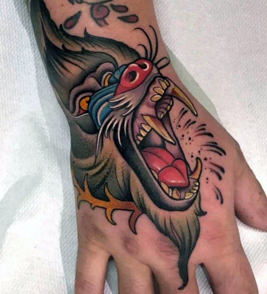 Neo-traditional baboon hand tattoo with bold outlines, vivid colors, and a fierce open-mouthed expression, creating a striking and dynamic design.