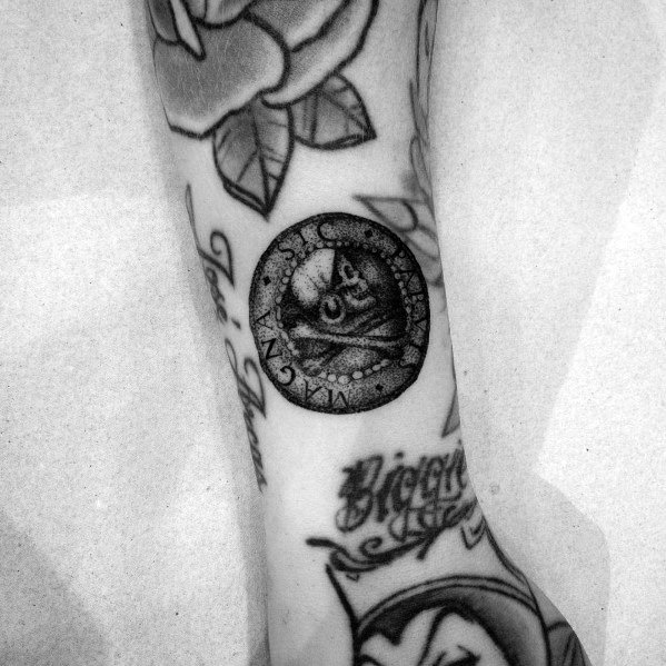 Detailed tattoo of an ancient coin with an owl design, featuring fine dotwork shading and intricate lettering on the forearm.