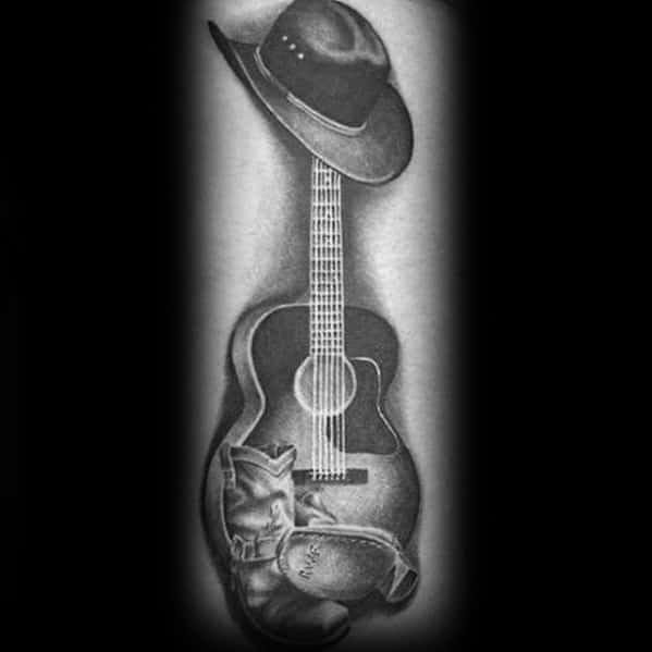 Black and gray tattoo of an acoustic guitar with a cowboy hat on top and boots at the base, done in a realistic Western style with fine shading.