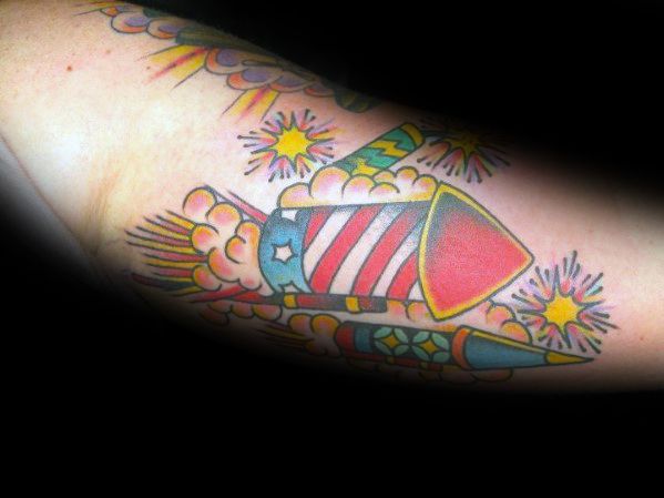 Tattoo of patriotic firework rockets with an American flag design, bursting with bright sparks and clouds, in a bold and colorful traditional style.