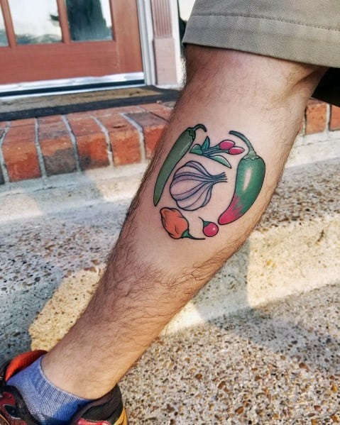 Colorful garlic and chili pepper tattoo on the leg, featuring bold outlines and vibrant shading for a lively and dynamic botanical design.