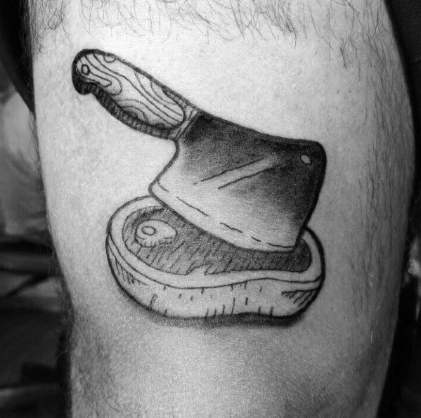 Black and gray tattoo of a cleaver resting on a steak, featuring bold shading and fine details for a classic butcher-inspired design