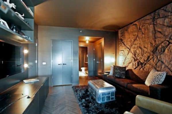 Modern living room with dark walls, a large sofa, a textured feature wall, and a metallic coffee table