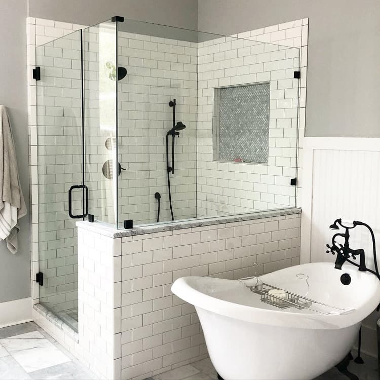 Modern bathroom with a glass shower, white subway tiles, and a standalone bathtub with black fixtures