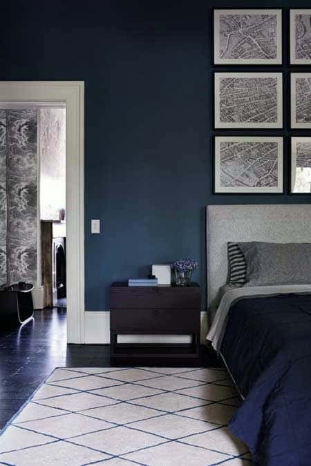 Framed map wall art arranged in a grid above a bed in a modern dark-toned bedroom.