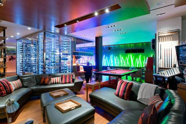 Luxury lounge with black sofas, pool table, wine rack, and colorful LED wall lighting