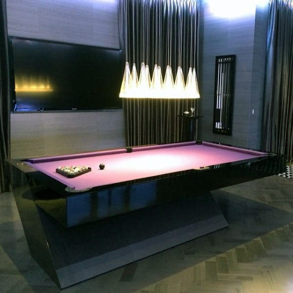 Elegant pool table with purple felt beneath modern lights and a large wall-mounted TV in a stylish room