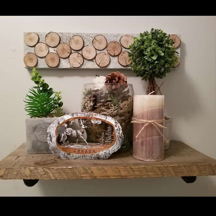 Rustic wooden bathroom shelf with candles, plants, and a Canada-themed decor piece.