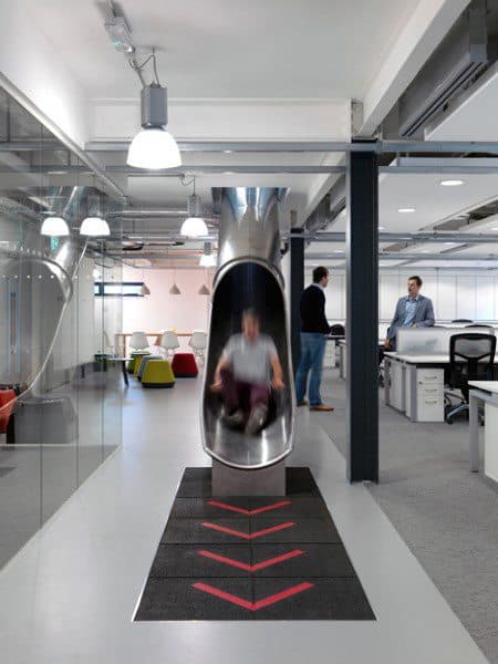 Office space with a slide, vibrant seating, and people chatting in the background