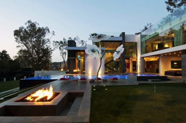 Modern house with large windows, an outdoor pool, a fire pit, and a giant flower sculpture in the yard