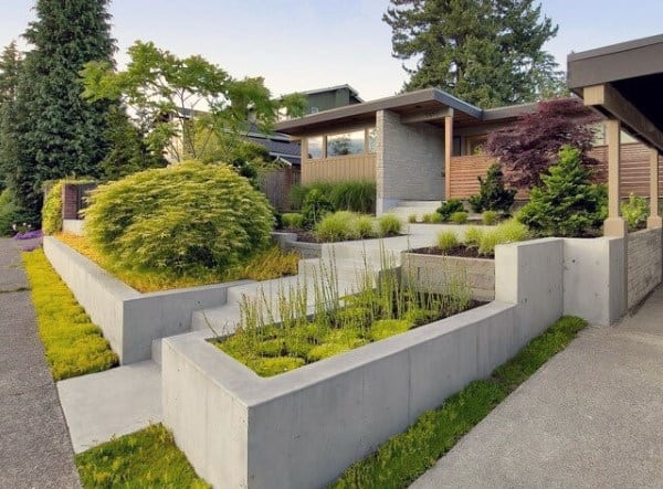 Modern front yard with tiered concrete planters, lush greenery, and minimalist design elements.