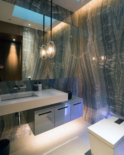 Modern bathroom with marble walls, floating vanity, pendant lights, and subtle under-cabinet lighting.