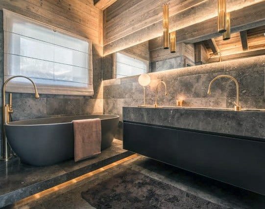 Rustic bathroom with a freestanding tub, dual sinks, and warm lighting