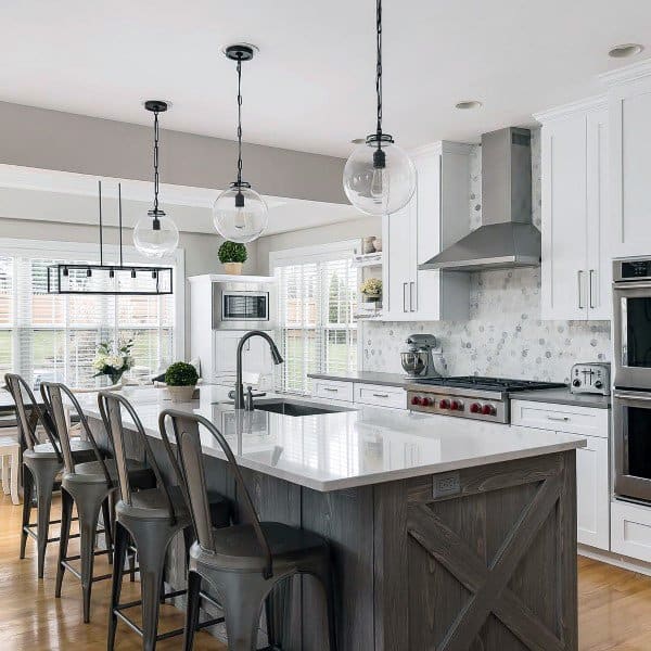 Bright modern rustic kitchen featuring a white island, barn-style details, and sleek pendant lighting.