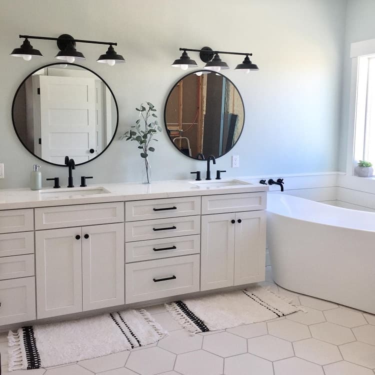 Modern farmhouse bathroom with double vanity, round mirrors, black fixtures, and a white freestanding tub