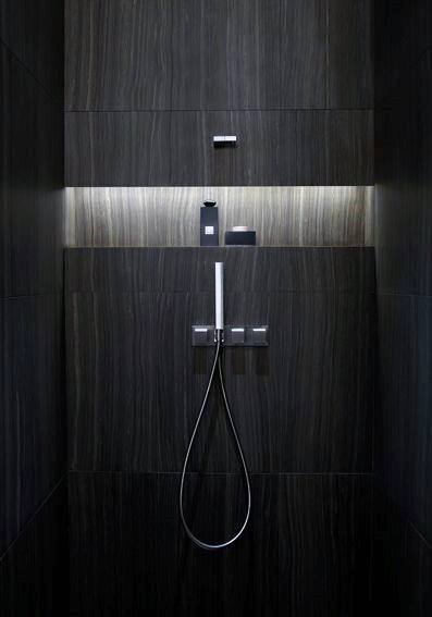 Modern shower with dark wood-textured tiles, minimal lighting, and sleek chrome fixtures.