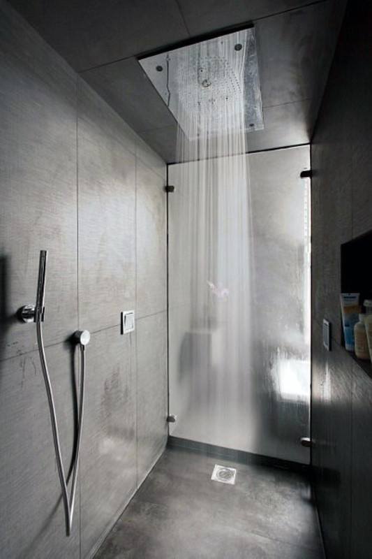 Modern shower with ceiling rainfall head, gray tiles, and sleek handheld fixture.