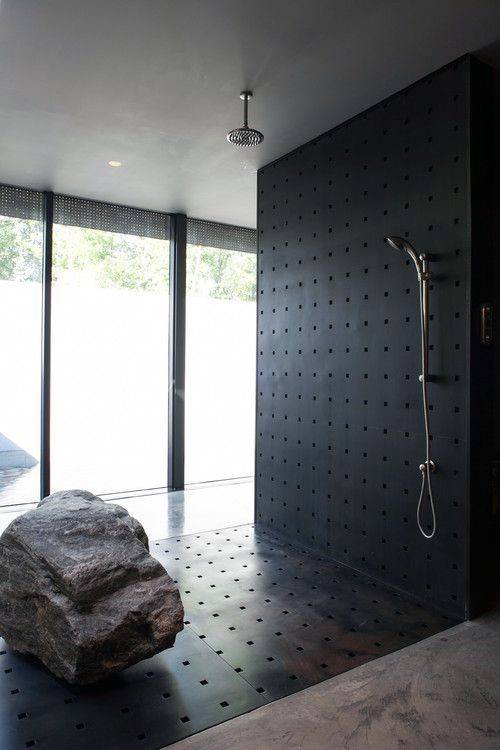 Modern shower with black textured wall, rainfall showerhead, and natural stone accent piece.