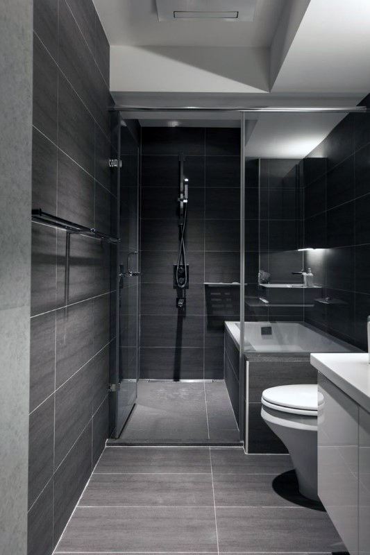 Dark modern bathroom with walk-in shower, glass enclosure, and sleek fixtures.