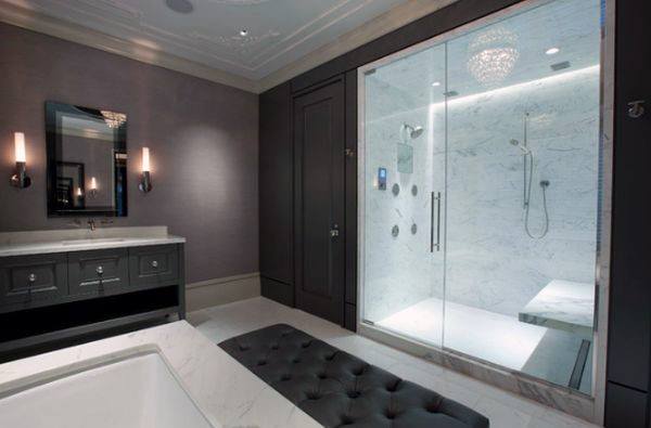 Luxurious bathroom with glass-enclosed marble shower, dark vanity, and elegant chandelier lighting.