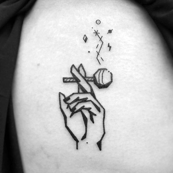 Minimalist black ink tattoo of a hand elegantly holding a lollipop, surrounded by abstract symbols and lines for a mystical, artistic touch.