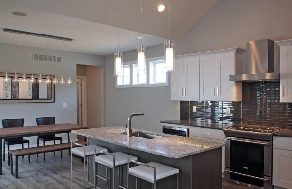 Modern kitchen with gray island, granite countertop, white cabinets, and pendant lighting.