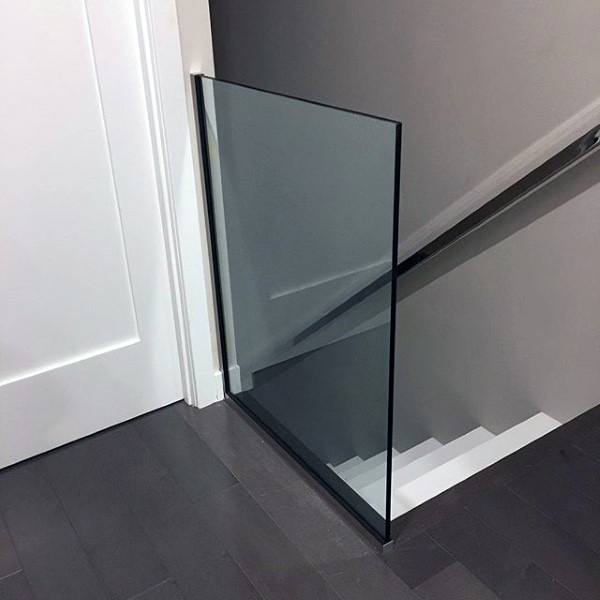 A clear glass panel guards the top of the staircase, adjacent to a closed white door
