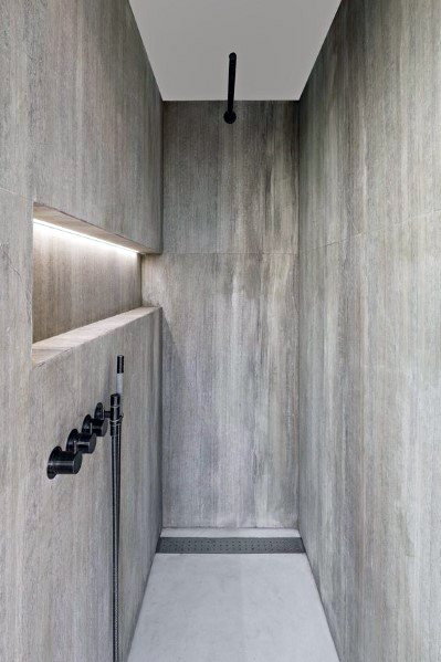 Minimalist shower with textured walls, recessed LED lighting along the niche, and sleek black fixtures for a modern, clean design