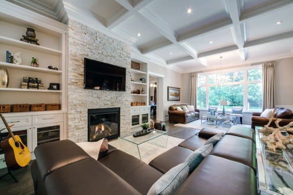Bright living room with a sleek stone fireplace, built-in shelves, and coffered ceiling.