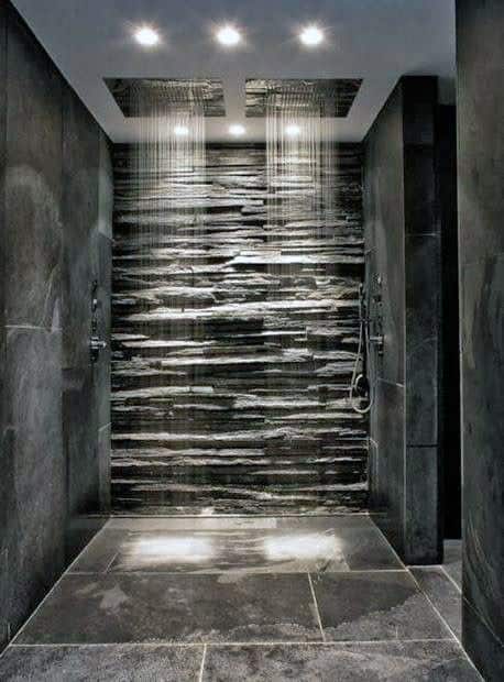 Luxury shower with slate stone wall, dual rainfall showerheads, and dark textured tiles.